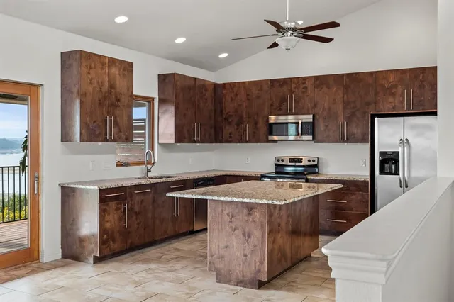 a kitchen with stainless steel appliances granite countertop a sink stove microwave and refrigerator