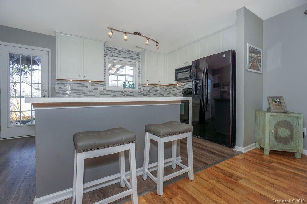 10029 Caldwell Depot Road Cornelius, NC 28031 - Photo 14 of 34 a kitchen with stainless steel appliances granite countertop a stove top oven a refrigerator and dining table with wooden floor