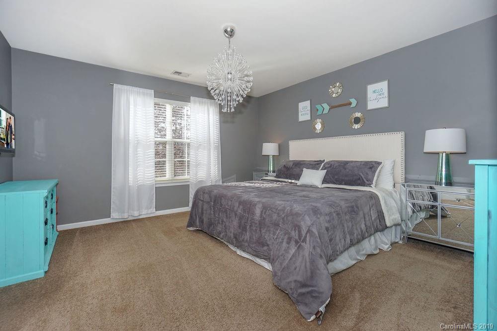 10029 Caldwell Depot Road Cornelius, NC 28031 - Photo 19 of 34 a spacious bedroom with a large bed and a chandelier