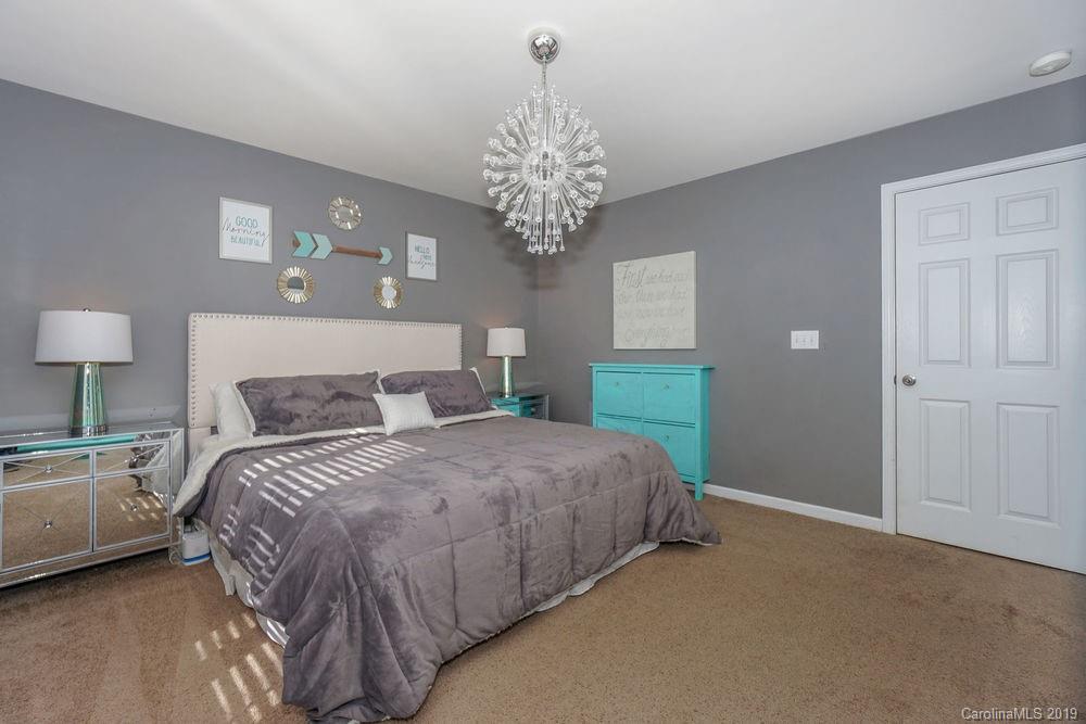 10029 Caldwell Depot Road Cornelius, NC 28031 - Photo 20 of 34 a spacious bedroom with a bed and a chandelier