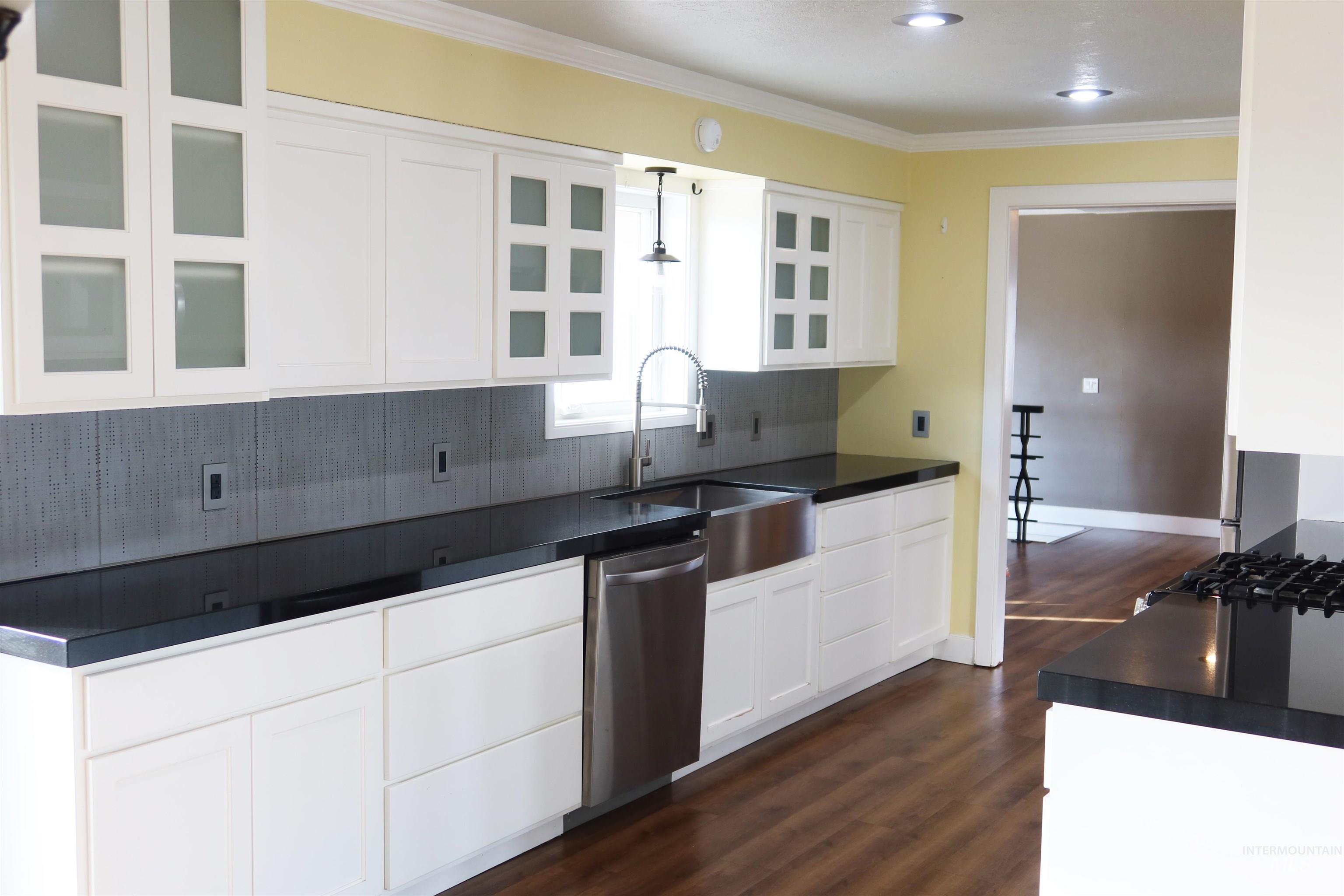 223 Hillcrest Road Burley, ID 83318 - Photo 8 of 27 Kitchen featuring decorative backsplash, white cabinetry, dark countertops, glass insert cabinets, and pendant lighting