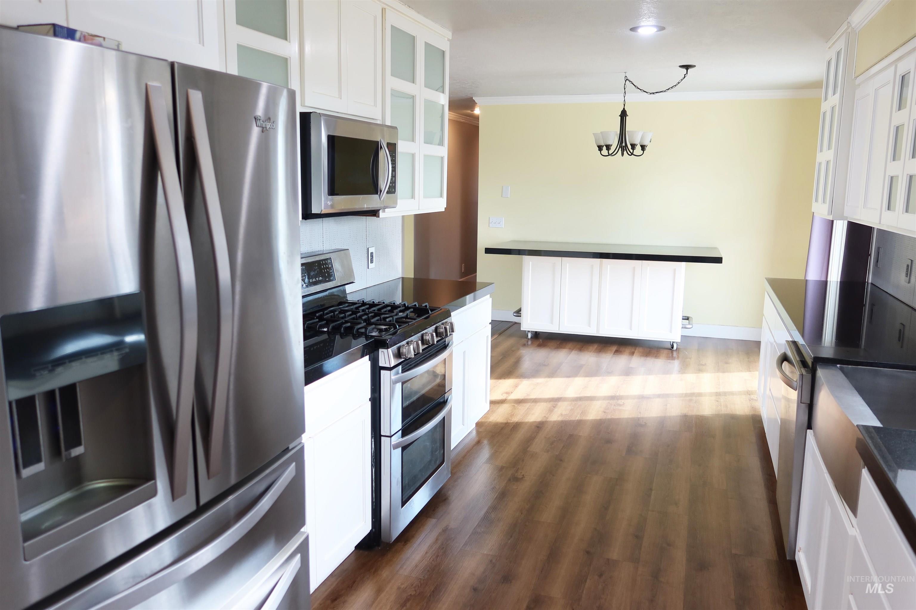 223 Hillcrest Road Burley, ID 83318 - Photo 9 of 27 Kitchen featuring dark countertops, stainless steel appliances, glass insert cabinets, white cabinetry, and crown molding