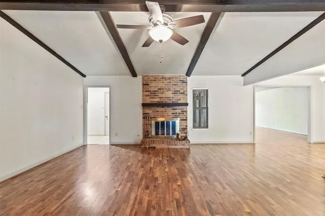 a view of an empty room with window and wooden floor