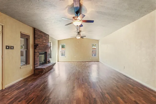 a view of a livingroom with wooden floor a ceiling fan and windows