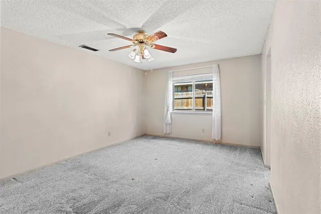 an empty room with windows and fan