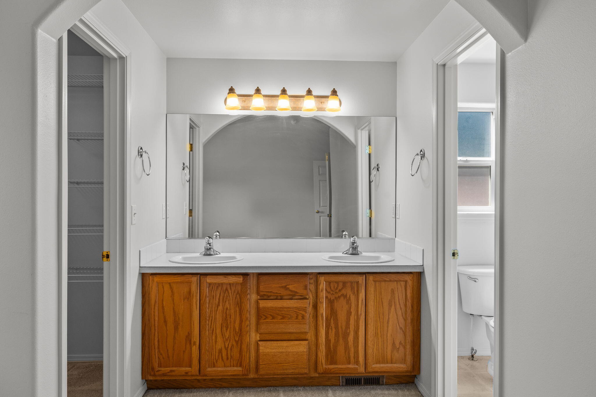 348 Northwest Antler Loop Redmond, OR 97756 - Photo 17 of 34 Primary suite double sinks, walk in closet to left, toilet and bath to right.