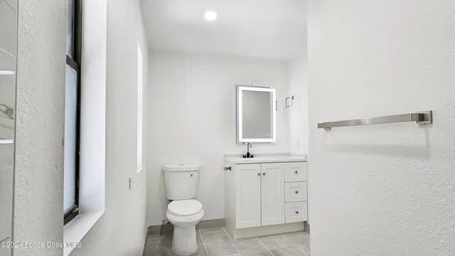 a bathroom with a granite countertop toilet sink and a mirror