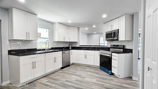 a kitchen with granite countertop a sink and steel appliances
