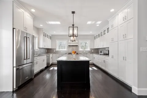 a kitchen with kitchen island white cabinets and stainless steel appliances