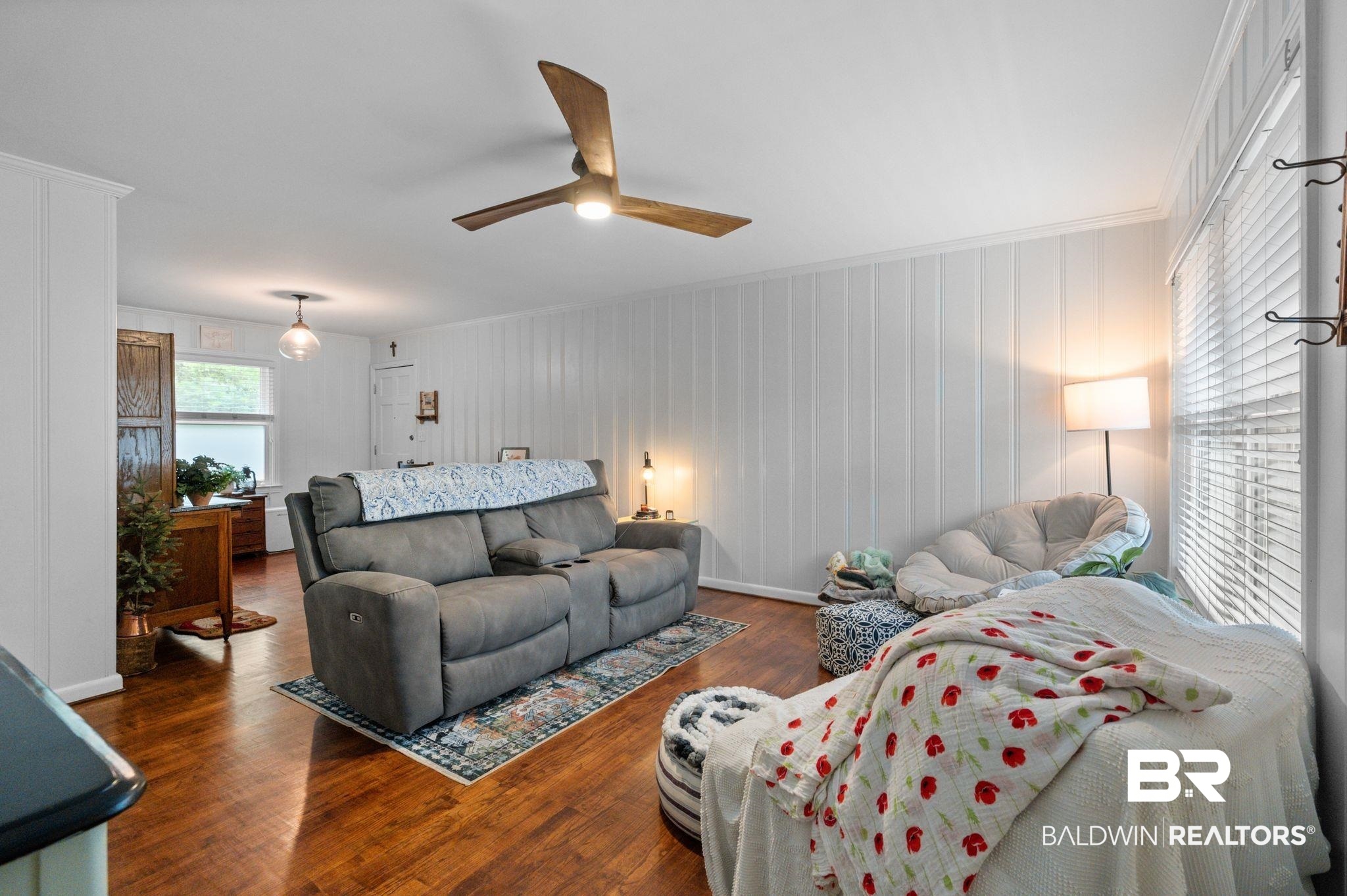 5417 Windmill Drive Mobile, AL 36693 - Photo 5 of 26 Spacious room featuring wood-finish flooring, white vertical plank walls, a ceiling fan with integrated lighting, and multiple windows with blinds
