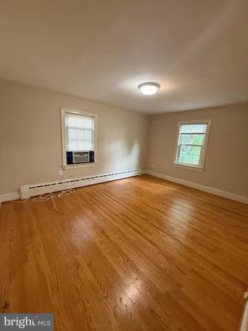a view of an empty room with window and wooden floor