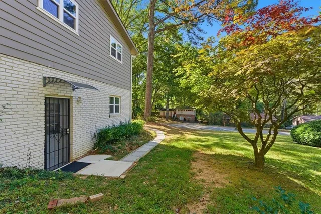 a view of a backyard with plants and large tree