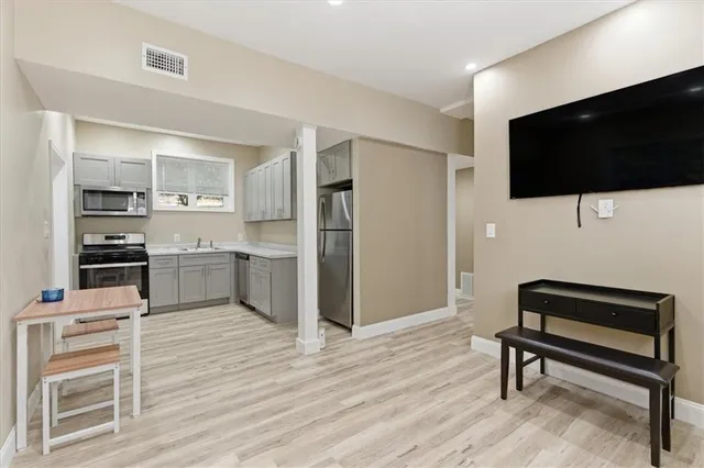a living room with stainless steel appliances furniture and a flat screen tv