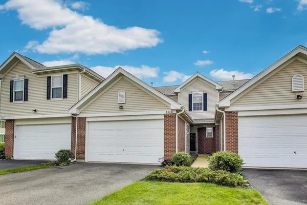 a front view of white house with a yard and garage