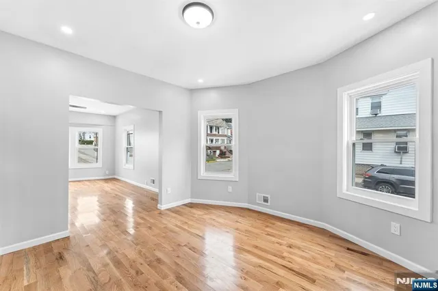 a view of empty room with window and wooden floor