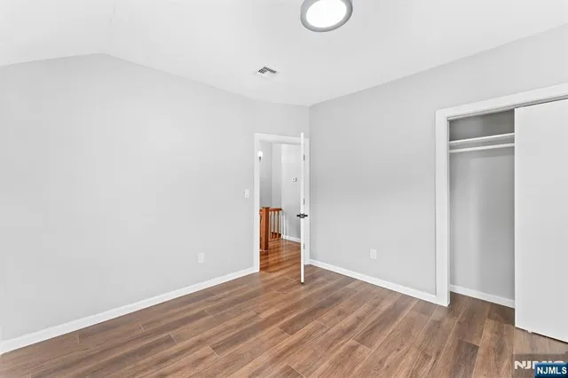 a view of empty room with wooden floor and bathroom