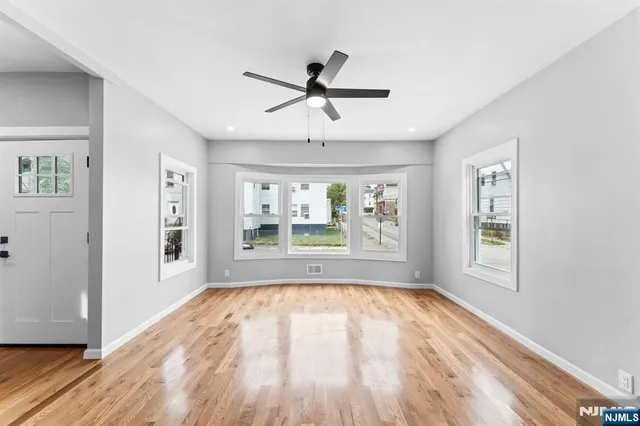 a view of an empty room with a window and wooden floor