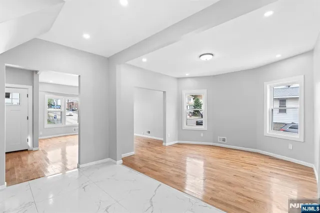 a view of an empty room with window and wooden floor