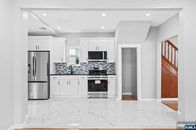a kitchen with white cabinets and stainless steel appliances