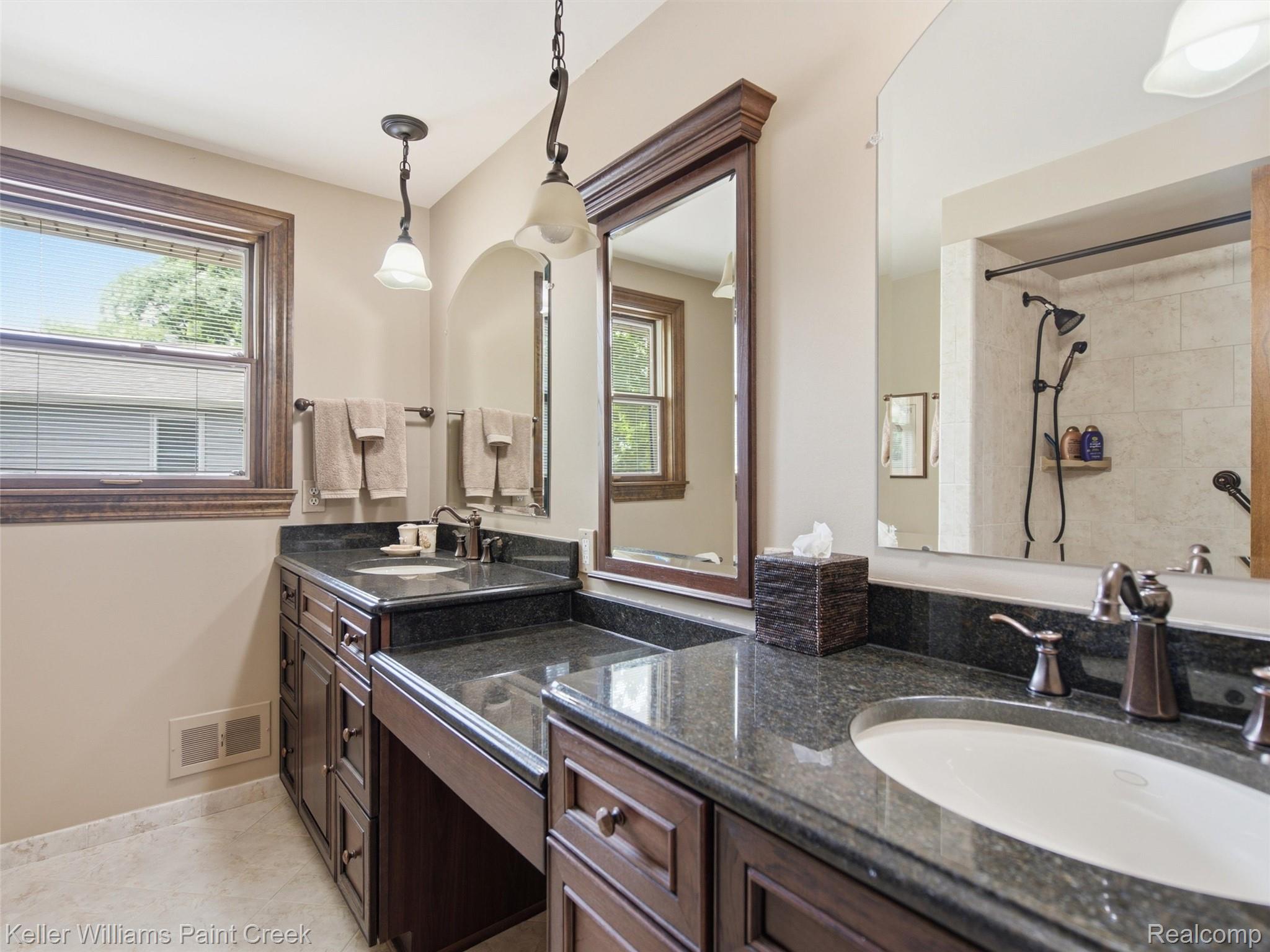 2950 Leyton Court Rochester, MI 48306 - Photo 22 of 46 Dual vanity with dark wood cabinetry, dark stone countertops, and undermount sinks