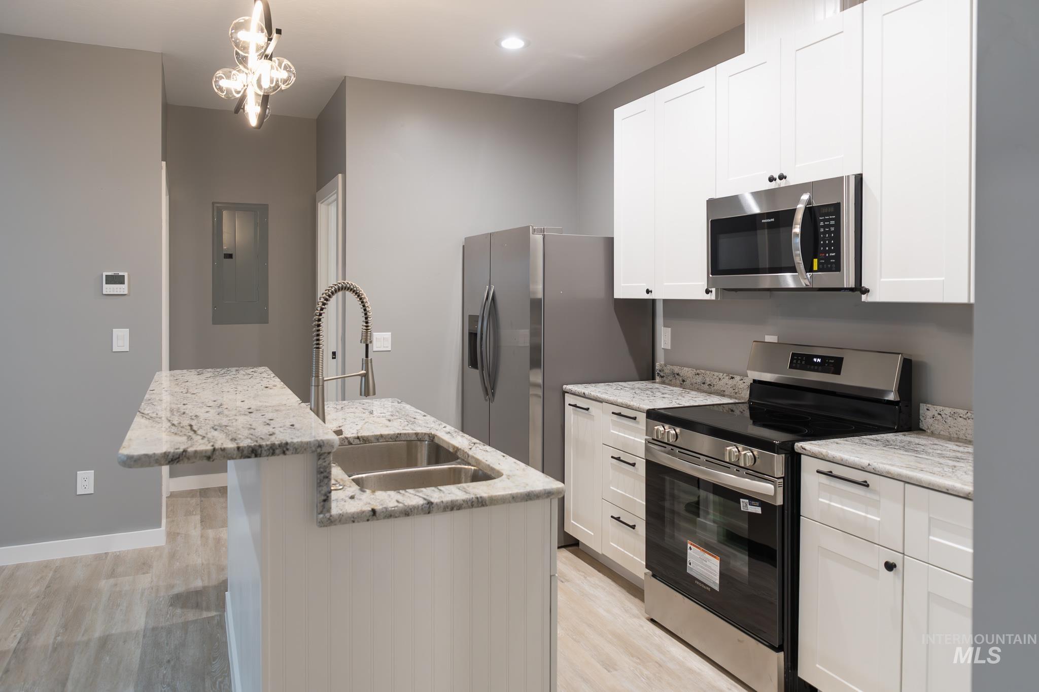 297 Southwest 6th Street, Unit 2 Ontario, OR 97914 - Photo 5 of 37 Kitchen with stainless steel appliances, light stone countertops, light wood-type flooring, and white cabinetry