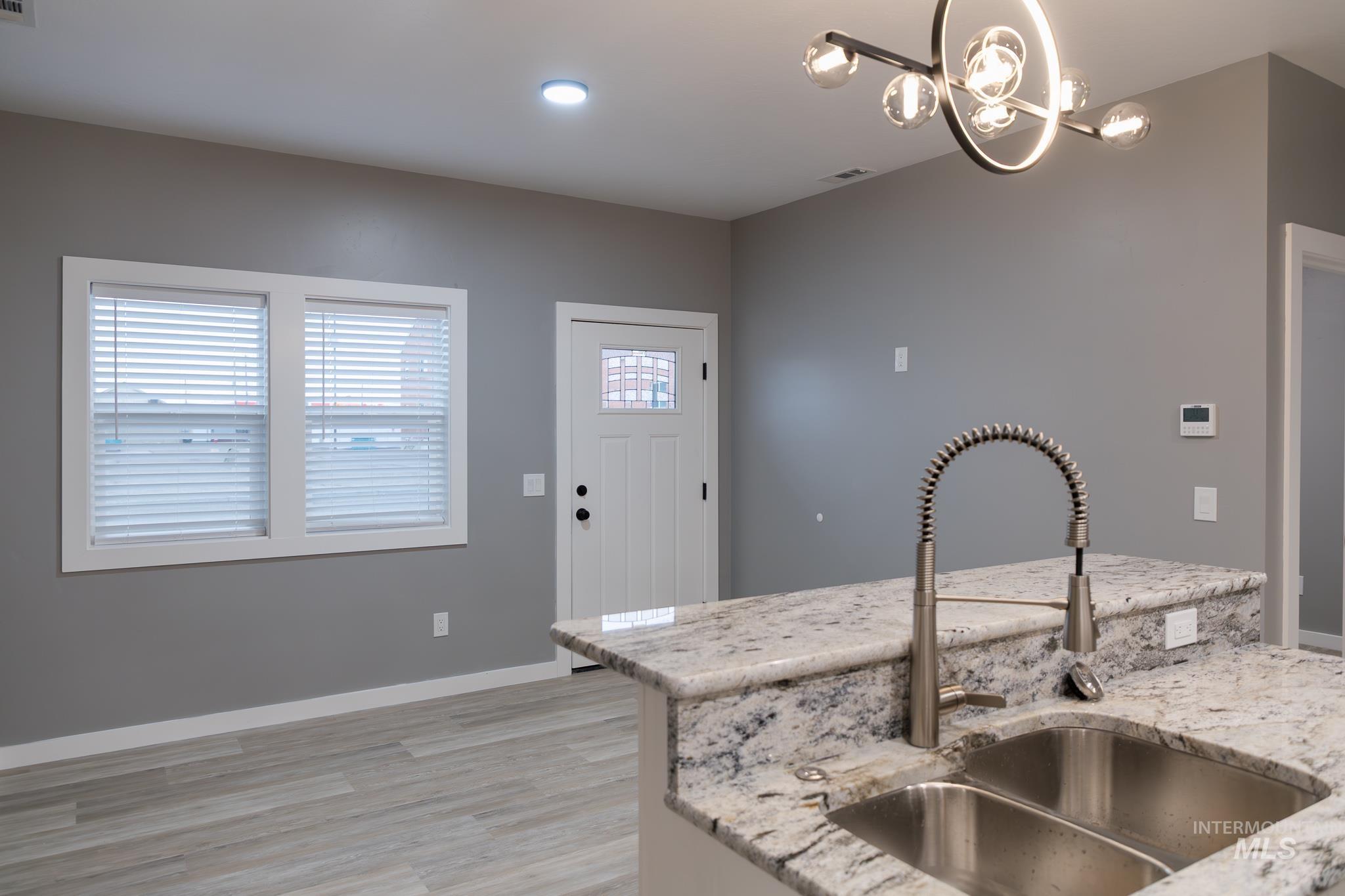 297 Southwest 6th Street, Unit 2 Ontario, OR 97914 - Photo 6 of 37 Kitchen with light stone countertops, hanging lights, and light wood-type flooring