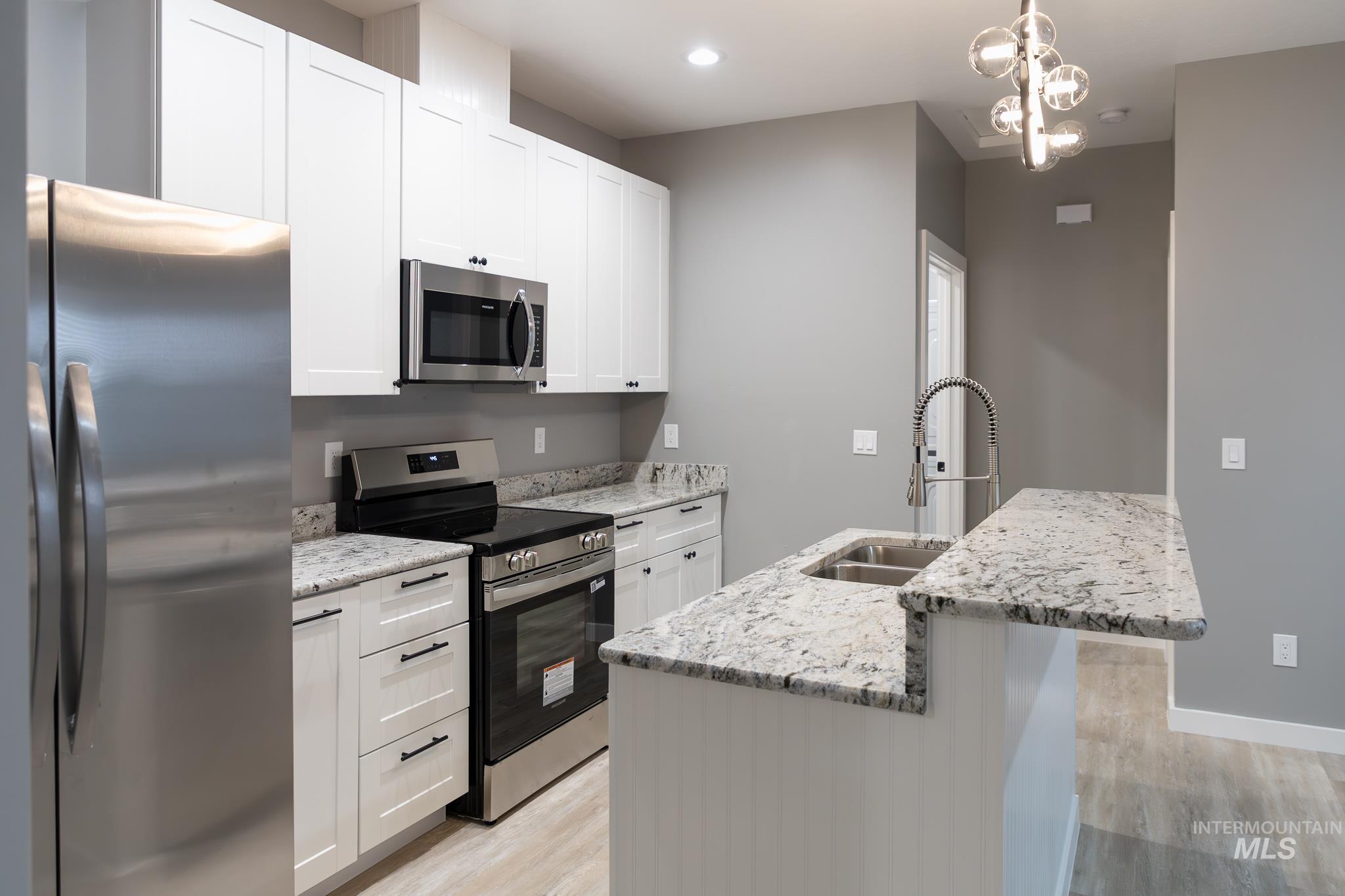 297 Southwest 6th Street, Unit 2 Ontario, OR 97914 - Photo 8 of 37 Kitchen with stainless steel appliances, light stone countertops, light wood-style flooring, white cabinetry, and a breakfast bar
