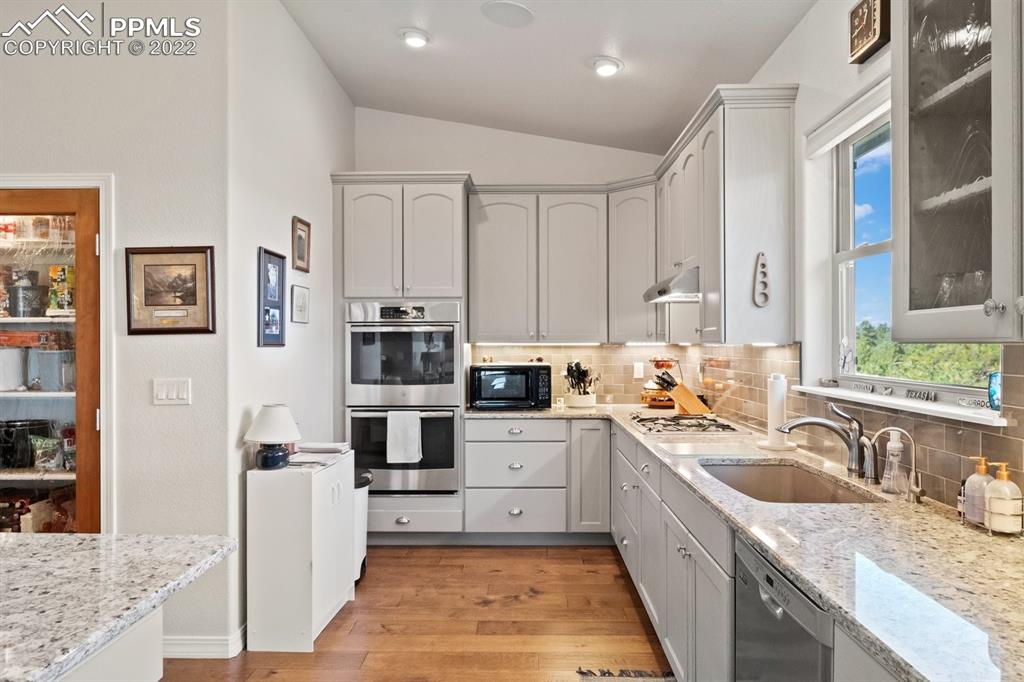 20765 Warriors Path Drive Peyton, CO 80831 - Photo 11 of 50 a large kitchen with stainless steel appliances granite countertop a sink and dishwasher a stove top oven with wooden floor