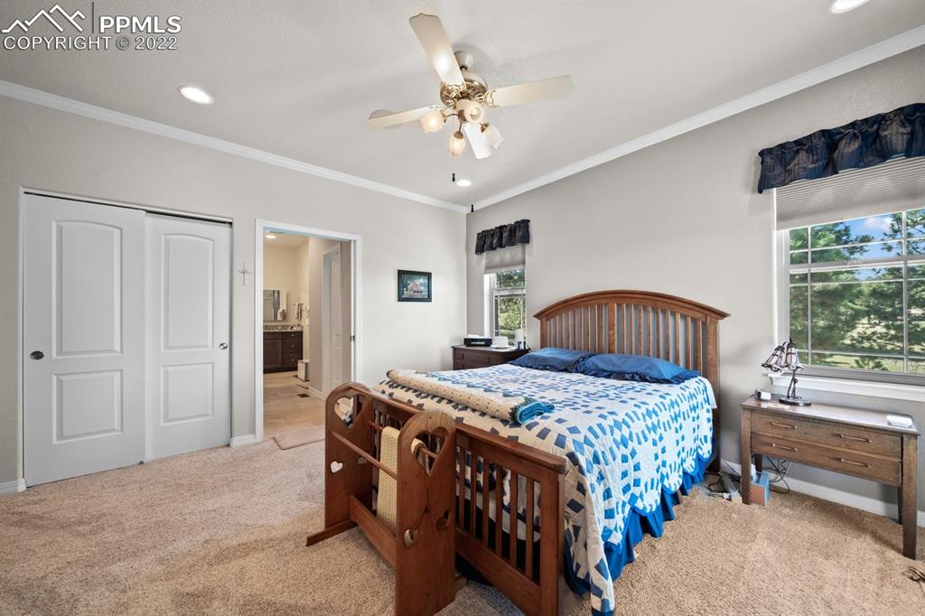 20765 Warriors Path Drive Peyton, CO 80831 - Photo 26 of 50 a bedroom with a bed a chandelier and dresser