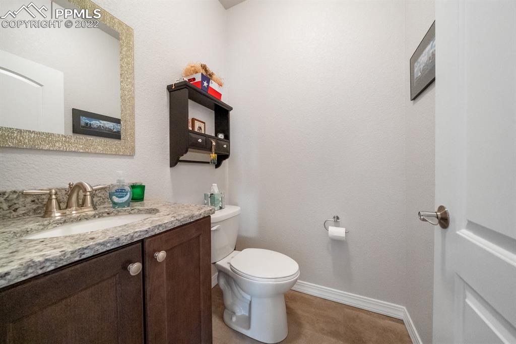 20765 Warriors Path Drive Peyton, CO 80831 - Photo 44 of 50 a bathroom with a granite countertop toilet sink mirror and vanity