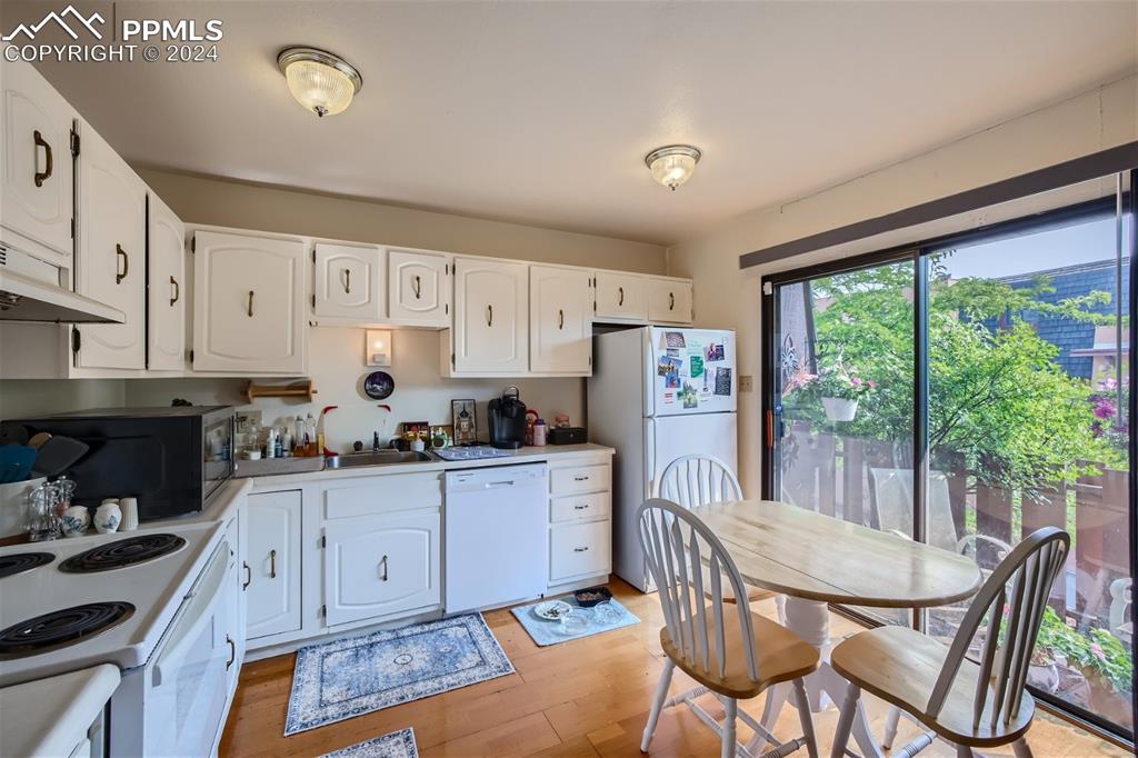 2913 Mesa Road, Unit A Colorado Springs, CO 80904 - Photo 6 of 15 a kitchen with stainless steel appliances granite countertop a stove a refrigerator a sink dishwasher a dining table and chairs with wooden floor