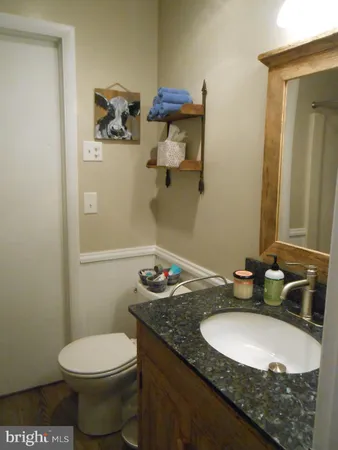 a bathroom with a granite countertop sink a toilet and a mirror