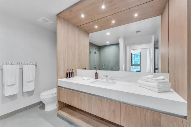 a en suite bathroom with a double vanity sink toilet and a mirror