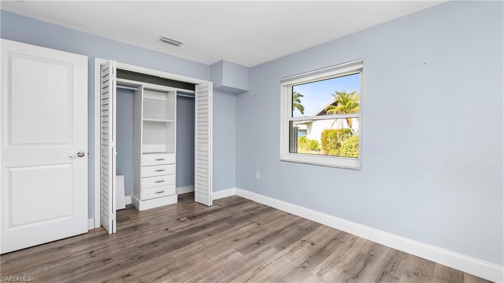 54 Hilo Court, Unit 54 Naples, FL 34112 - Photo 17 of 42 an empty room with wooden floor closet and windows