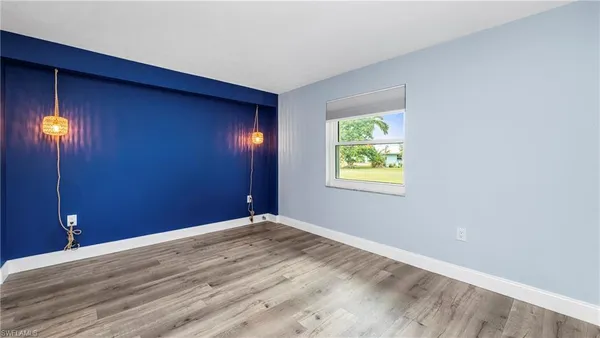an empty room with wooden floor closet and windows