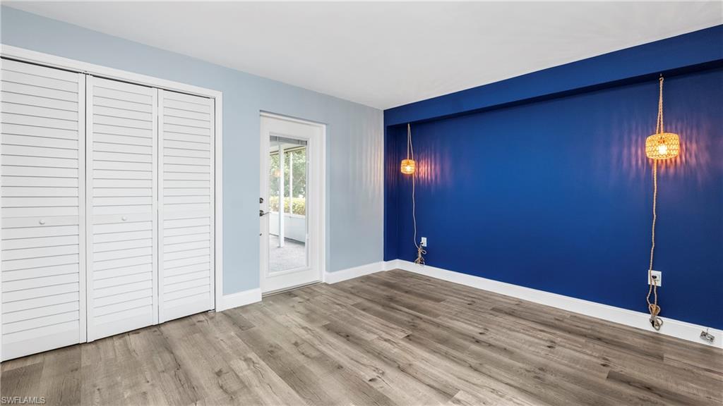 54 Hilo Court, Unit 54 Naples, FL 34112 - Photo 19 of 42 an empty room with wooden floor and windows