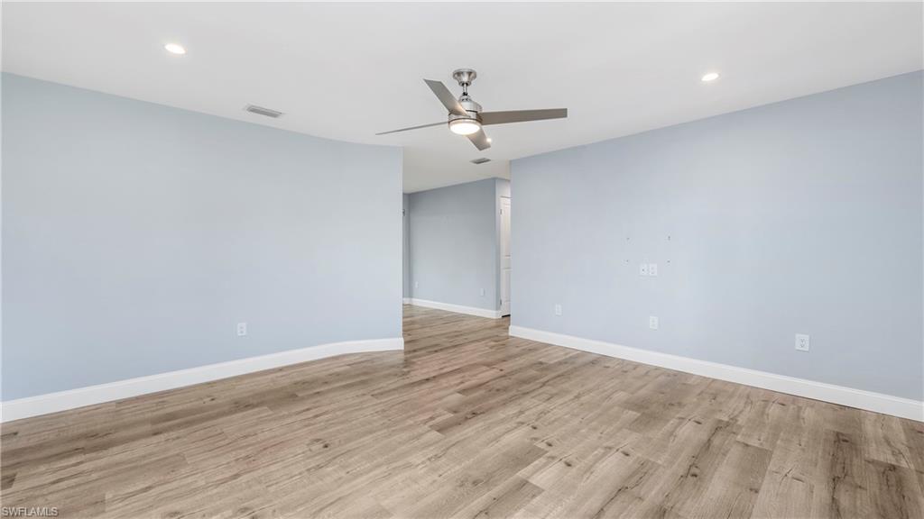 54 Hilo Court, Unit 54 Naples, FL 34112 - Photo 7 of 42 an empty room with wooden floor ceiling fan and windows