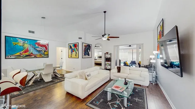 a living room with furniture kitchen view and a wooden floor