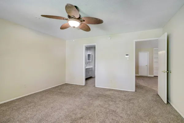 a view of an empty room and chandelier fan