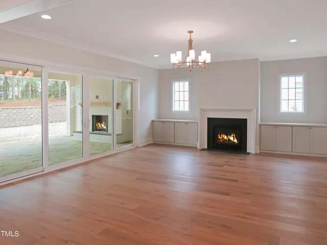 an empty room with fireplace chandelier and windows