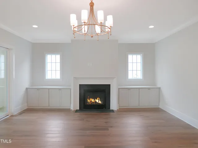 a view of an empty room with wooden floor fireplace and a window