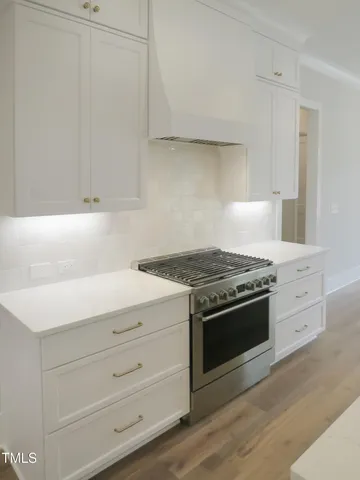 a kitchen with a sink a stove a refrigerator and white cabinets