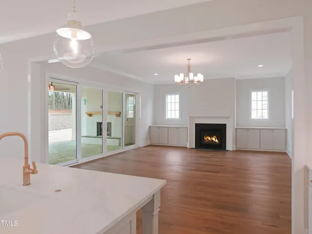 a view of a livingroom with a fireplace a chandelier and wooden floor