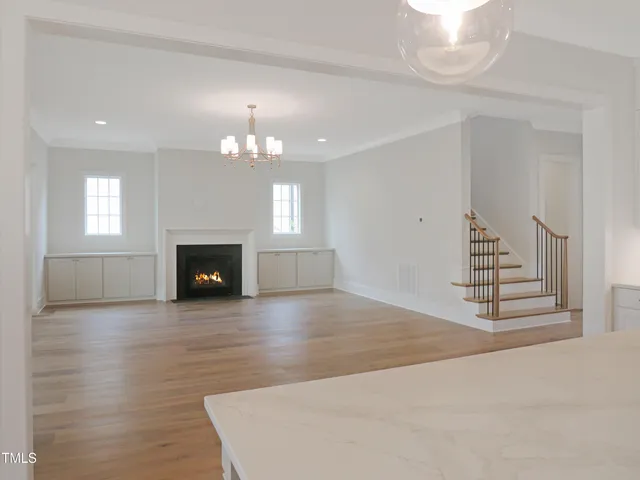 an empty room with a fireplace and chandelier