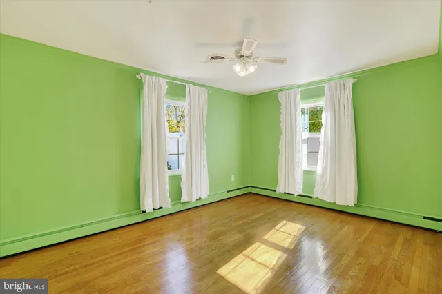 a view of an empty room with window and chandelier fan