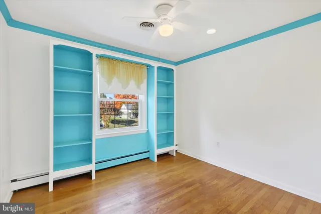 an empty room with wooden floor closet and windows