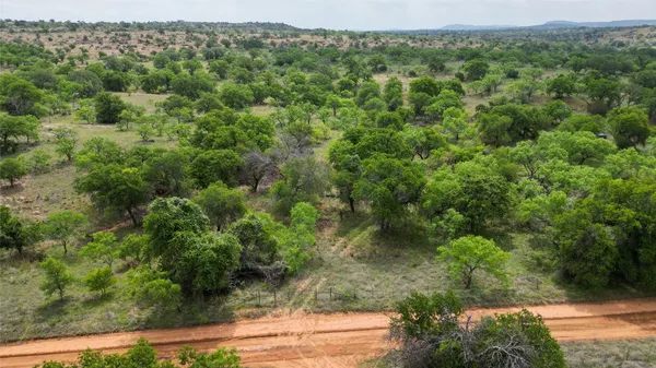 an aerial view of residential houses with outdoor space and trees all around