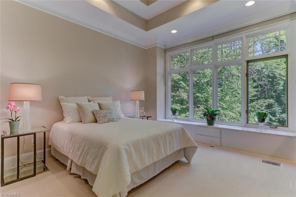 5260 Bunch Road Summerfield, NC 27358 - Photo 16 of 30 Bedroom 2 on the main level is carpeted, has a double tray ceiling, recessed ceiling lights, built-in window seat with storage and features an en-suite bath.