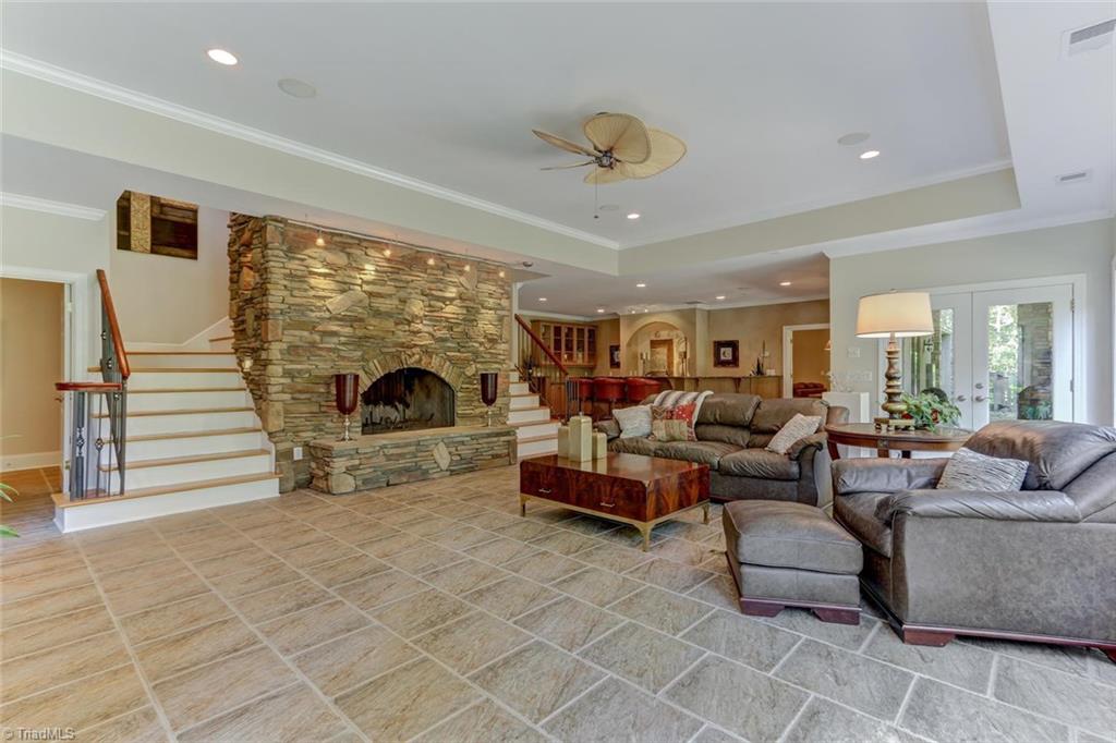 5260 Bunch Road Summerfield, NC 27358 - Photo 19 of 30 Lower level Great Room has tile floor, wood burning stone fireplace with raised hearth. Stairs from main level descend on either side of fireplace. French doors to patio. Recessed ceiling lights and fan.