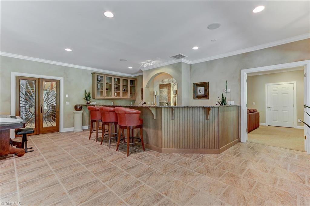 5260 Bunch Road Summerfield, NC 27358 - Photo 20 of 30 Lower Level bar features granite countertops, sink, dishwasher, ice maker and refrigerator. Cut-glass doors are to wine cellar.